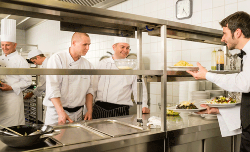 Cocineros y camarero en la cocina de un restaurante
