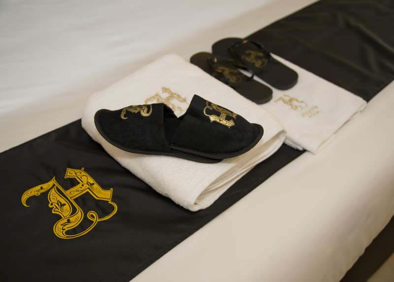 Toallas y zapatillas bordadas en el Hugo's Hotel Boutiqye